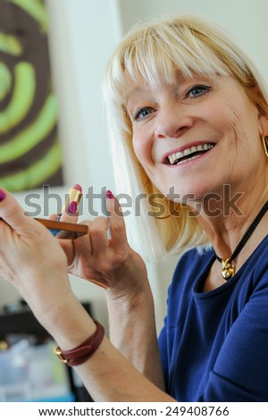 Portrait of a happy woman putting on makeup Red lip, looking camera