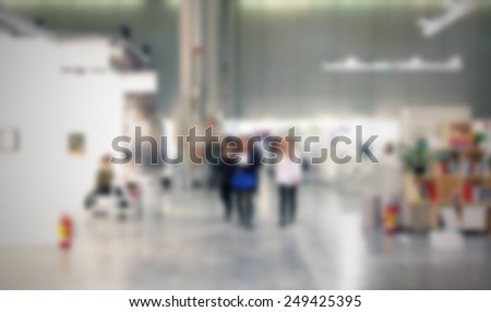 People visit an art gallery. Location, works and people not recognizable. Intentionally blurred post production background.