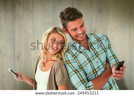 Attractive couple using their smartphones against wooden planks