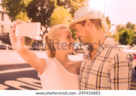 Young hip couple taking a selfie on a sunny day in the city