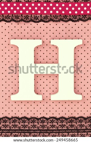 Wooden letter H on polka dots background