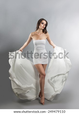 beautiful young girl in flying white dress. Flowing fabric
