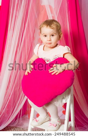 Little girl with a heart toy in pink tutu skirt