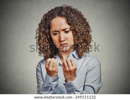 Closeup portrait worried woman looking at hands fingers nails obsessing about cleanliness isolated grey wall background. Negative human emotion facial expression feeling body language perception  Royalty-Free Stock Photo #249511132