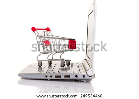 Studio shot of a  shopping cart over a laptop computer