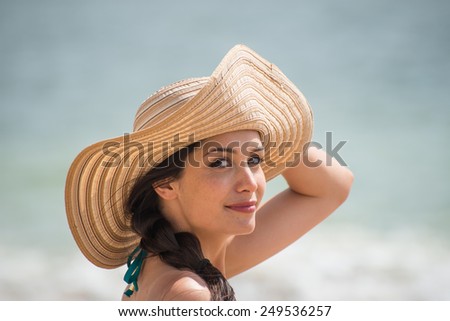 Portrait of a beautiful girl with a big hat at the beach, a loving woman is enjoying the sunlight in her swimsuit