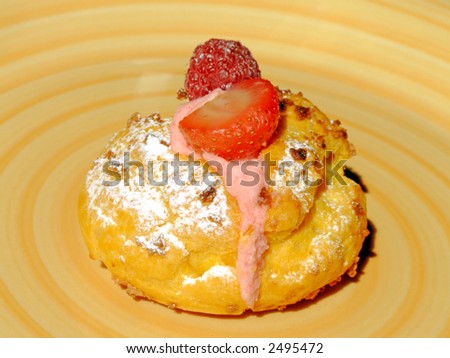 Puff dough filled with berries cream, decorated with strawberry, raspberry and icing sugar