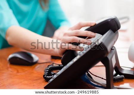 Close up on female hand holding phone at office desk