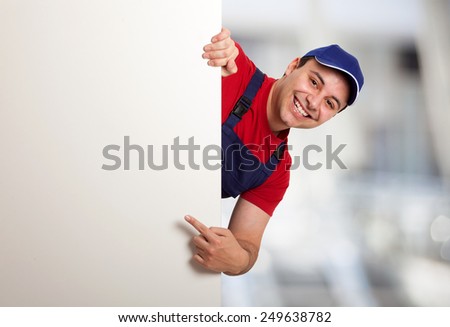Portrait of a friendly worker pointing his finger to a blank board