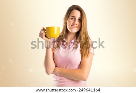 Blonde girl drinking coffee over ocher background 