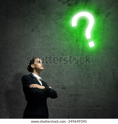Young businesswoman looking thoughtfully at question mark