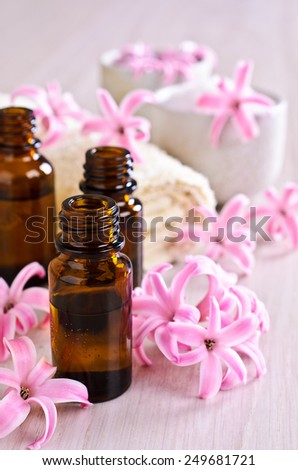 Aromatic oil for Spa in a glass vial surrounded by flowers pink hyacinth.