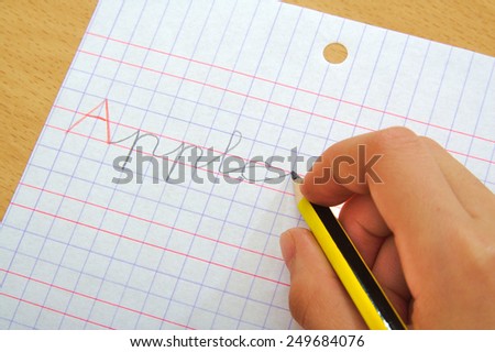 Closeup of the hand of a child writing apple word with a pencil. School concept