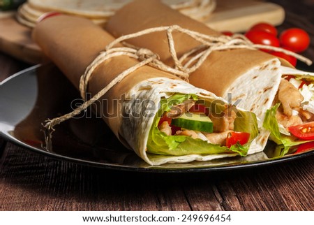 Mexican tortilla wrap with meat and vegetables on wood table