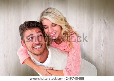 Handsome man giving piggy back to his girlfriend against wooden planks
