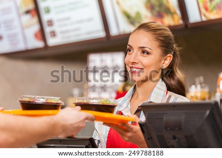 Restaurant worker serving two fast food meals with smile. woman holding tray with salads at fast food restaurant Royalty-Free Stock Photo #249788188