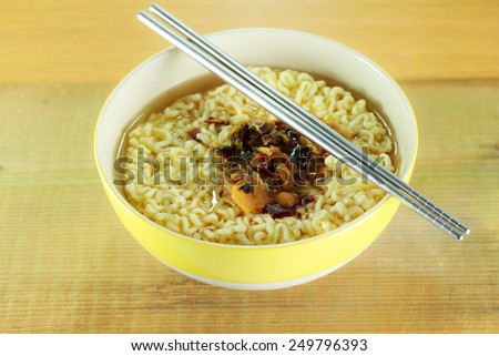 Instant noodles in yellow dish on wood background