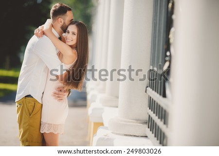 Couple in love kissing laughing having fun. Dating interracial young couple embracing on date. Pretty summer sunny outdoor portrait of young stylish couple while kissing on the street. Relationships