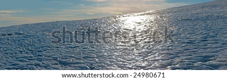Wind form ice texture on winter mountain snow surface in contra light direction - with sun catchlights (Seven shots stitch image)