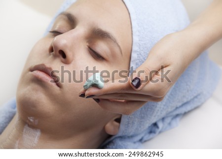 woman applaying facial mask to girl