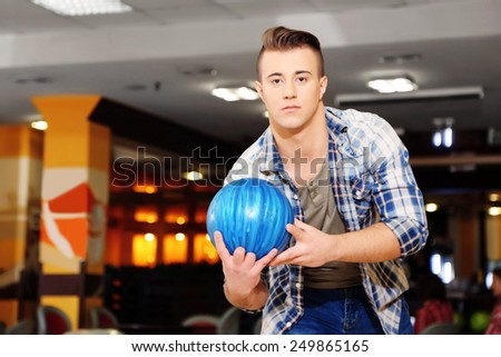 Young man playing bowling in club