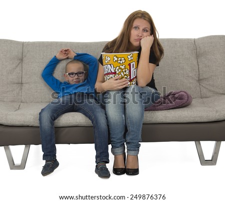 Mother and son watching a boring movie on a sofa while eating popcorn against a white background