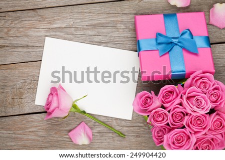 Valentines day greeting card or photo frame and gift box full of pink roses over wooden table. Top view