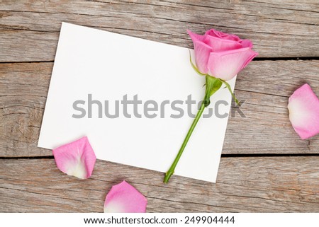 Valentines day greeting card or photo frame and pink rose over wooden table. Top view with copy space