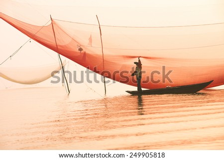 Unidentified fisherman checks his nets in early morning on river in Hoian, Vietnam Royalty-Free Stock Photo #249905818