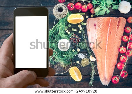 Salmon fillets on wooden background and blank screen mobile phone 