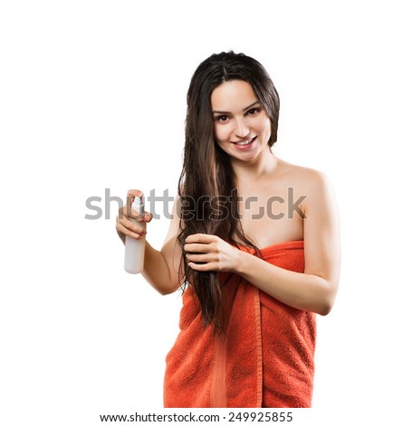 Beautiful young smiling long-haired woman wearing a towel applying hair conditioner isolated on white background