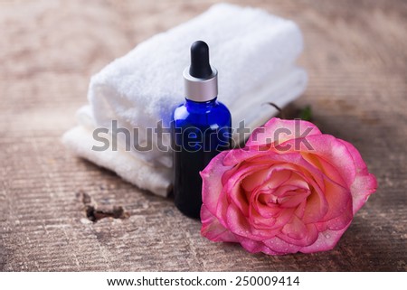 Essential aroma oil with rose on wooden background. Spa settiing. Selective focus.