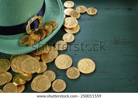 Happy St Patricks Day leprechaun hat with gold chocolate coins on vintage style green wood background with copy space. .
