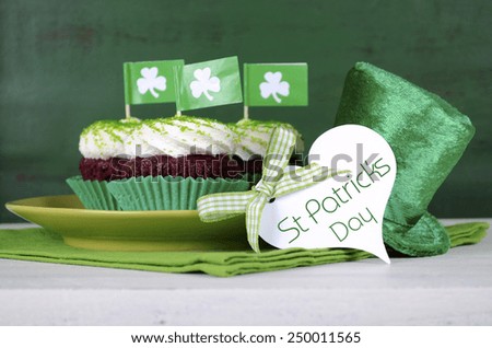 Happy St Patricks Day cupcakes with green theme decorations on vintage style green wood background.