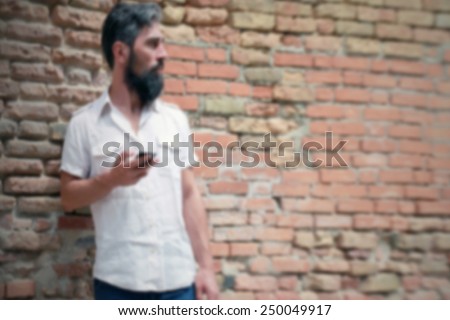 Man waiting with his smart phone. Intentionally blurred editing post production background.