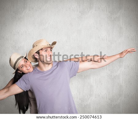 Man giving his pretty girlfriend a piggy back against weathered surface