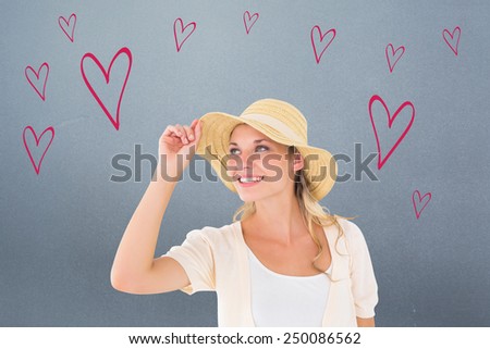 Attractive young blonde smiling in sunhat against grey