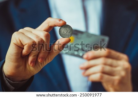 Business person holds russian five rouble coin and plastic credit card. Toned picture