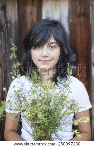 Young positive girl with a bouquet of wild flowers in the village
