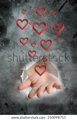 Hand bursting through paper against heart