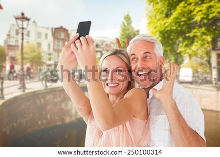 Happy couple posing for a selfie against bridge in amsterdam