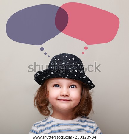 Smiling child dreaming about and looking on bubbles above head on grey background