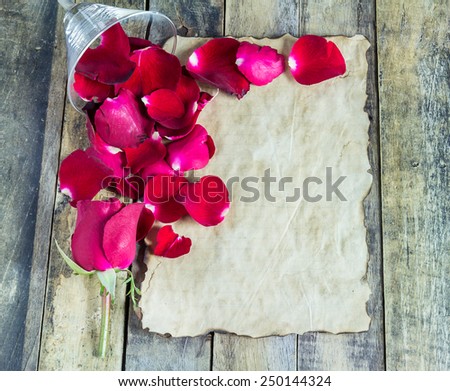 Fresh red rose and old paper on a wooden background. Holidays romantic background