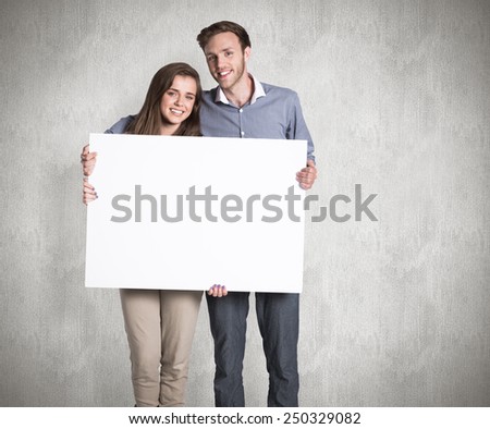 Full length portrait of couple with blank board against weathered surface