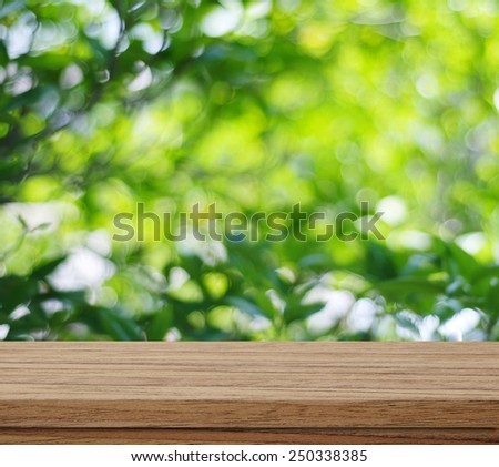 Empty wooden table over blur trees with bokeh background, for product display montage