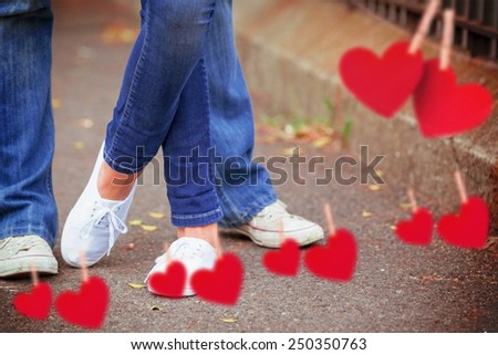 Hip young couple standing by railings against hearts hanging on a line