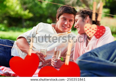 Man smiling as he looks at his friend during a picnic against hearts hanging on the line