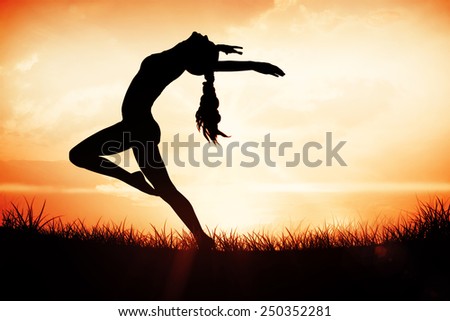 Side view of a sporty young woman stretching against orange sunrise