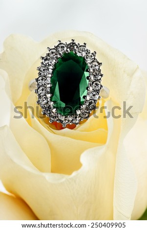 Generic Emerald diamond engagement ring tucked inside of a beautiful yellow rose. Extreme shallow depth of field with selective focus on ring.