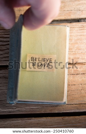 Believe in love concept. label and open book on the wooden background.